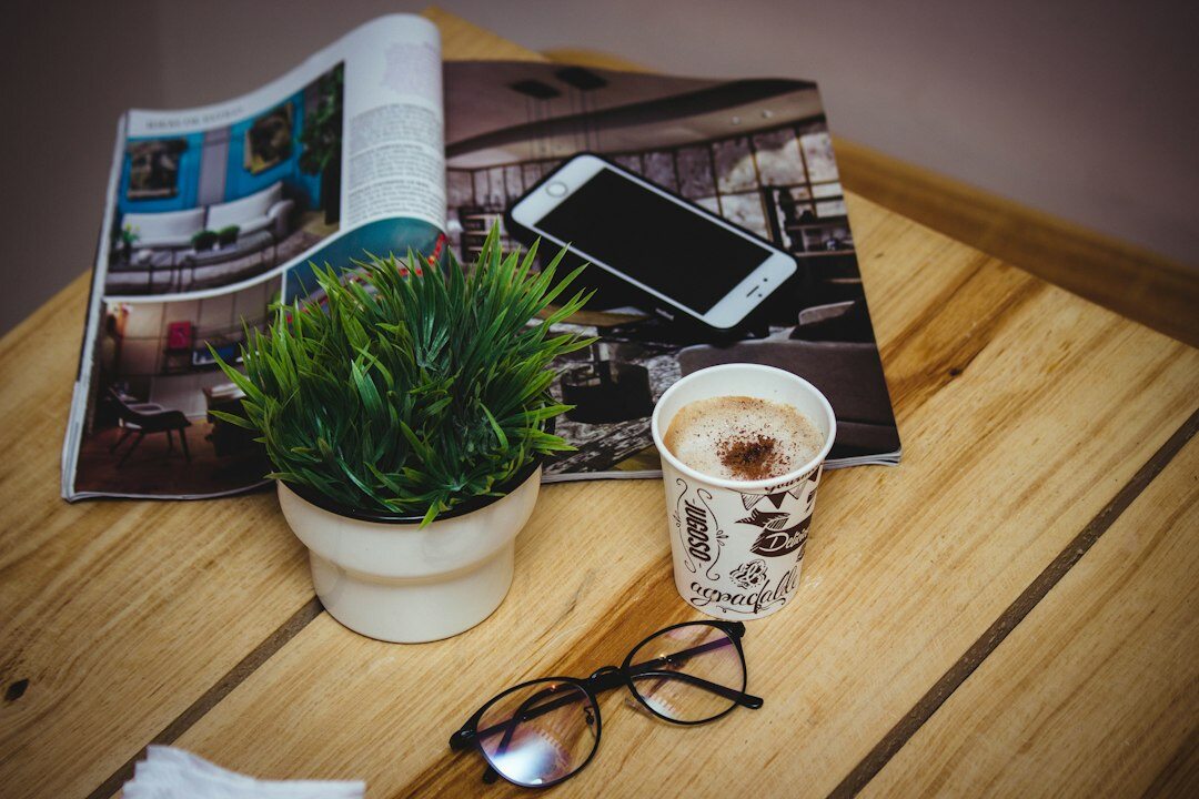 Stylish wooden desk with an open magazine, coffee cup and reading glasses